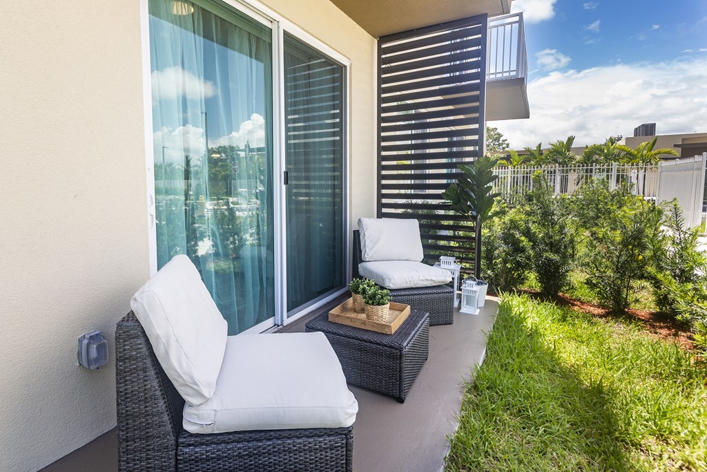 a patio with two wicker chairs and a glass sliding door