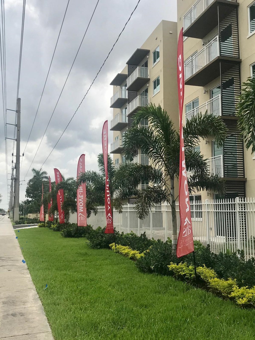 a row of red flags in the grass outside an apartment building
