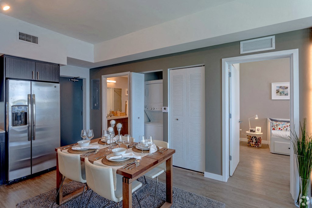 a dining room with a wooden table and chairs and a stainless steel refrigerator
