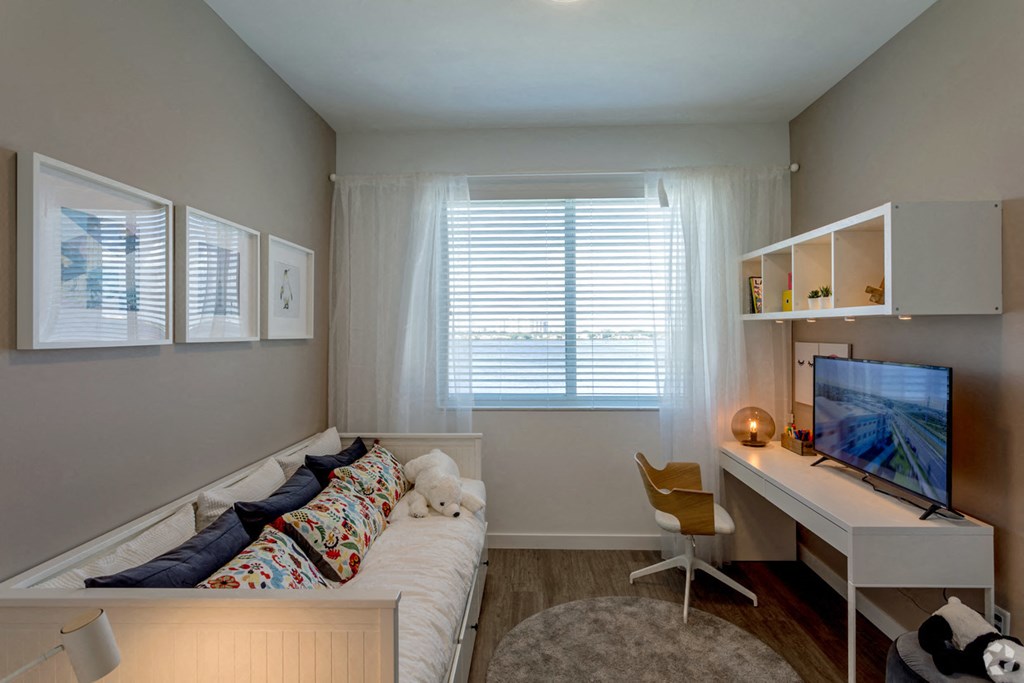 a bedroom with a bed and a desk and a television