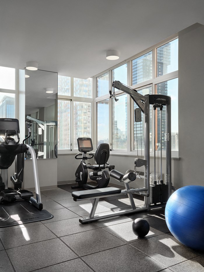 A gym with a variety of equipment including a leg press machine, a bench press, and a medicine ball.