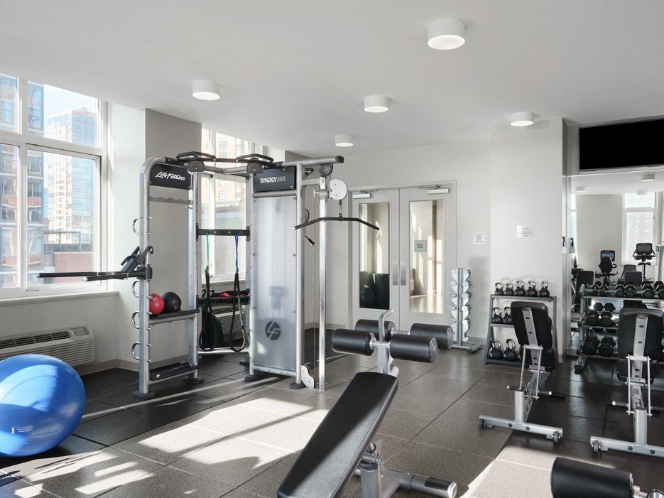 a gym with weights and other exercise equipment in a room with windows