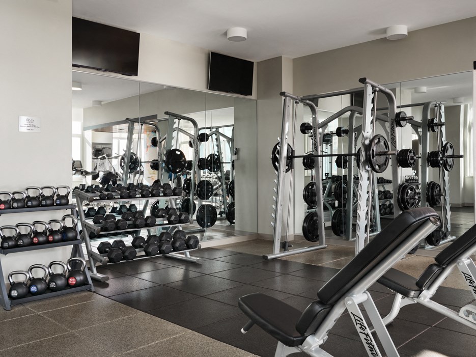 A gym with a variety of equipment including weights and weight machines.