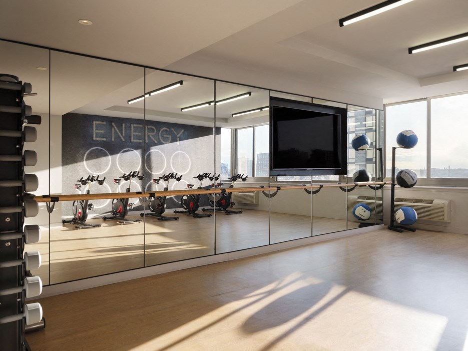A gym with a mirror wall and a television.