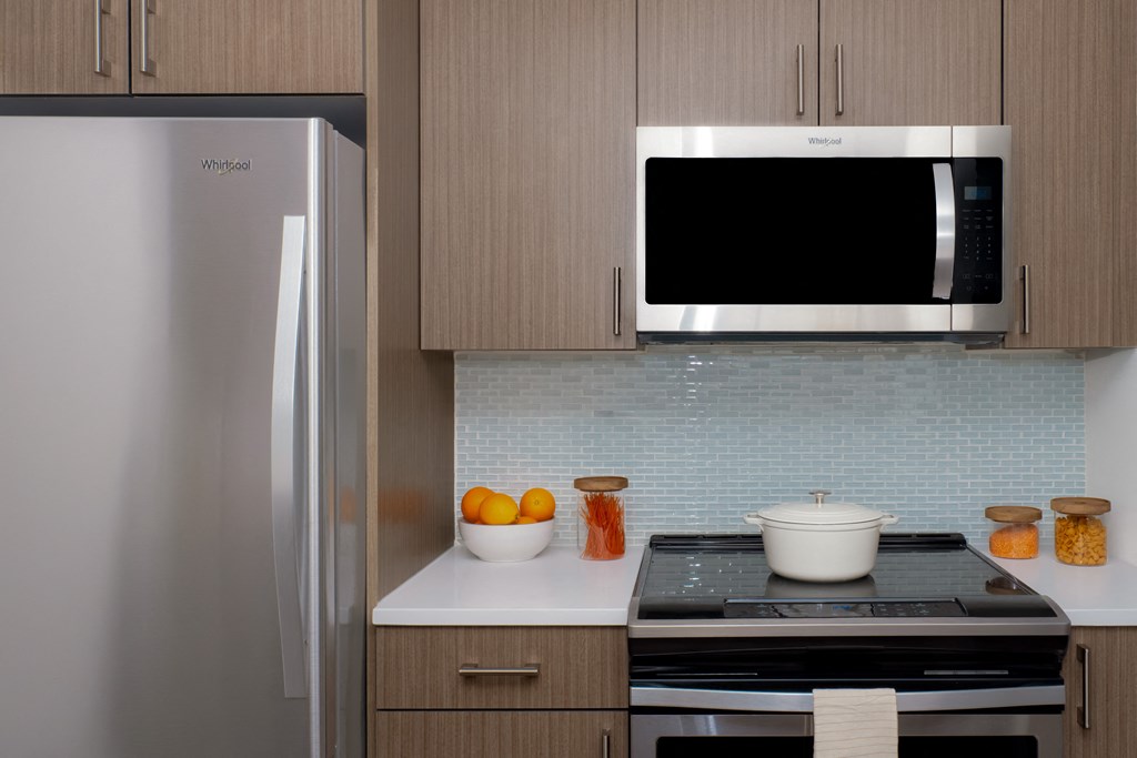 A kitchen with a refrigerator, microwave, and stove.