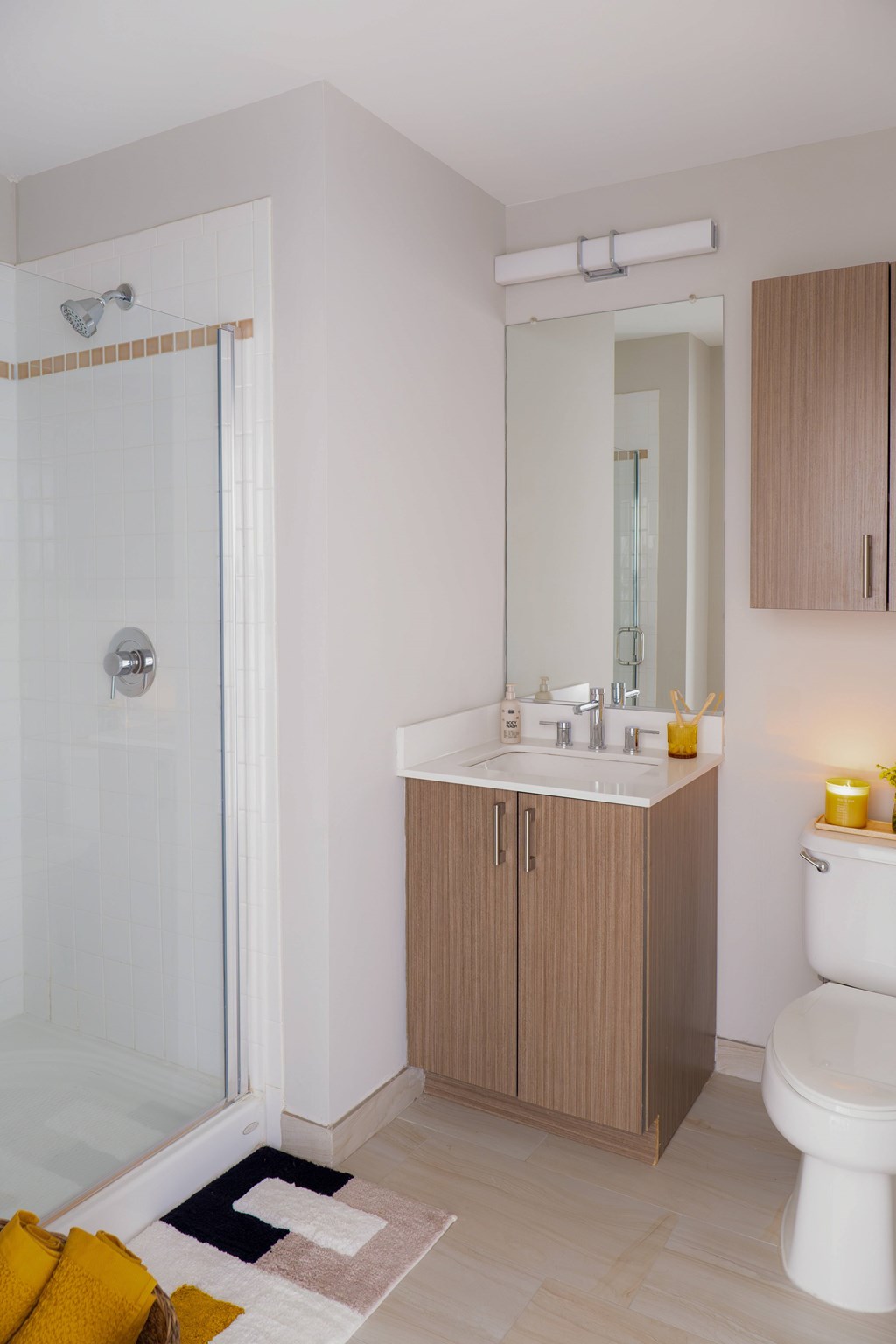 A bathroom with a white toilet, a sink with a mirror above it, and a glass shower stall.