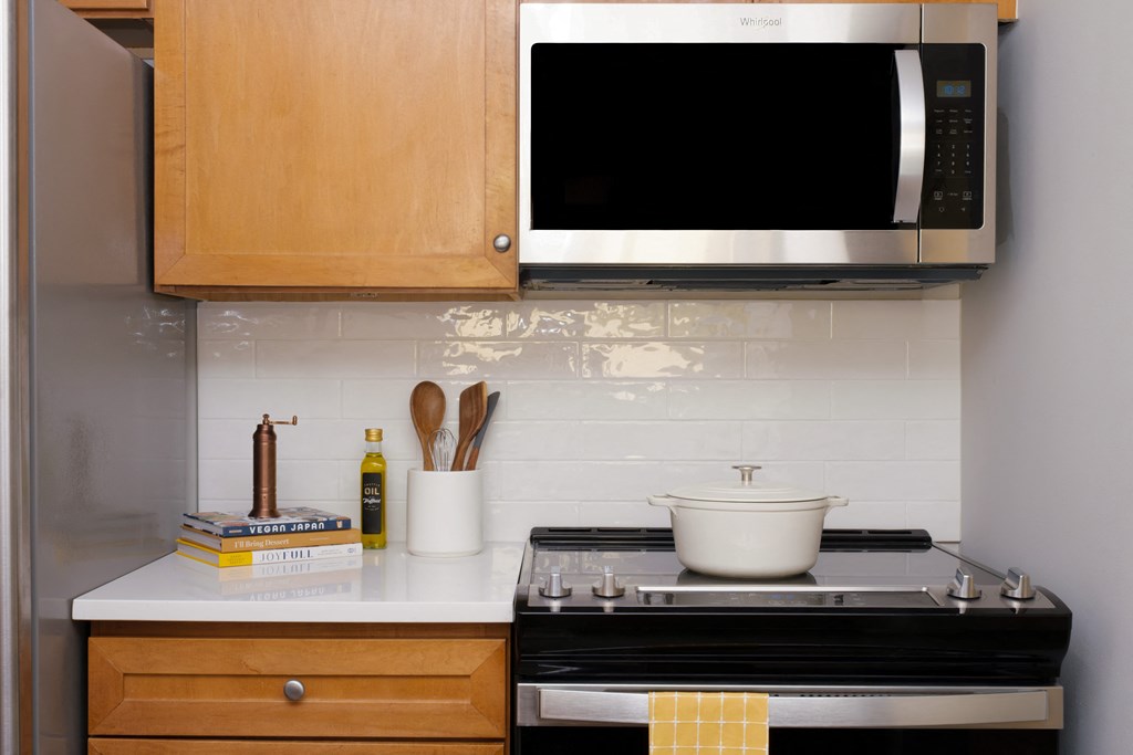 A kitchen with a stove, microwave, and utensils.