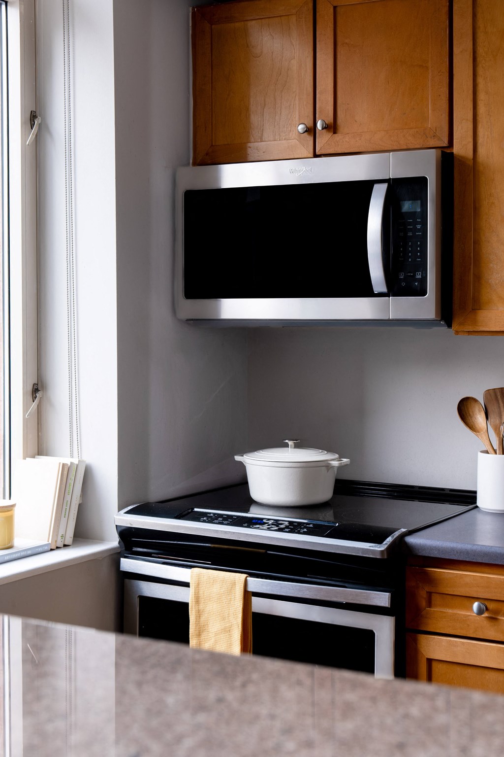 A black microwave is mounted above a stove in a kitchen.