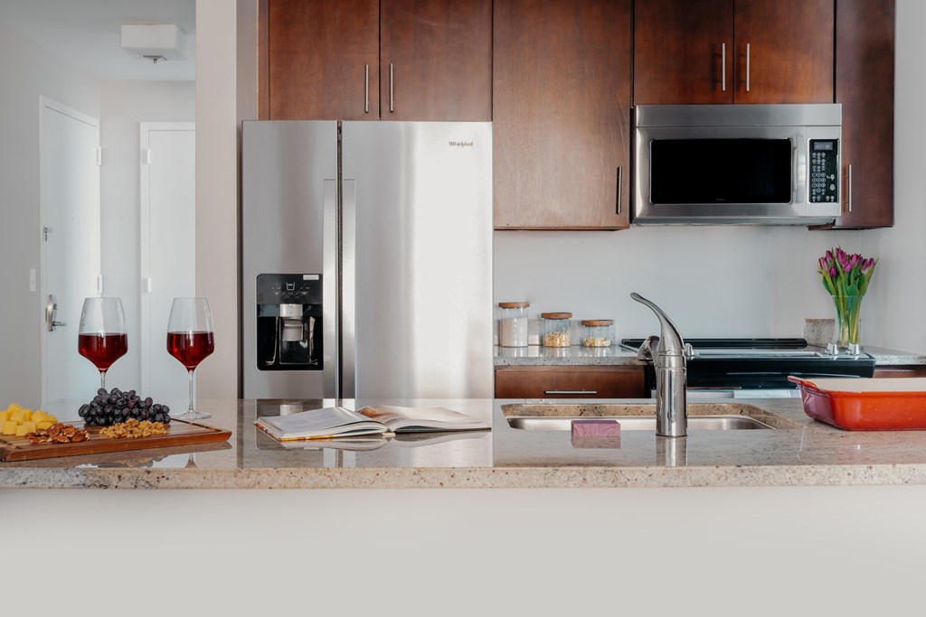 A kitchen with a refrigerator, microwave, and sink.