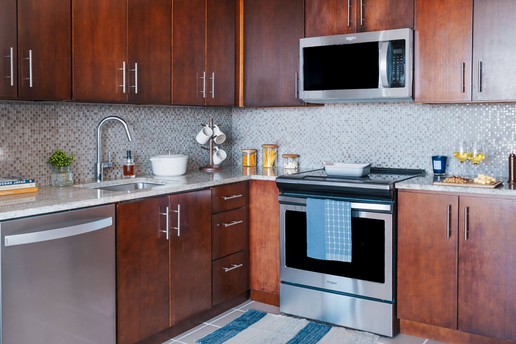 A modern kitchen with dark wood cabinets and stainless steel appliances.