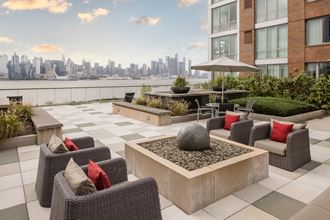 an outdoor terrace with chairs and a fire pit with a view of the city