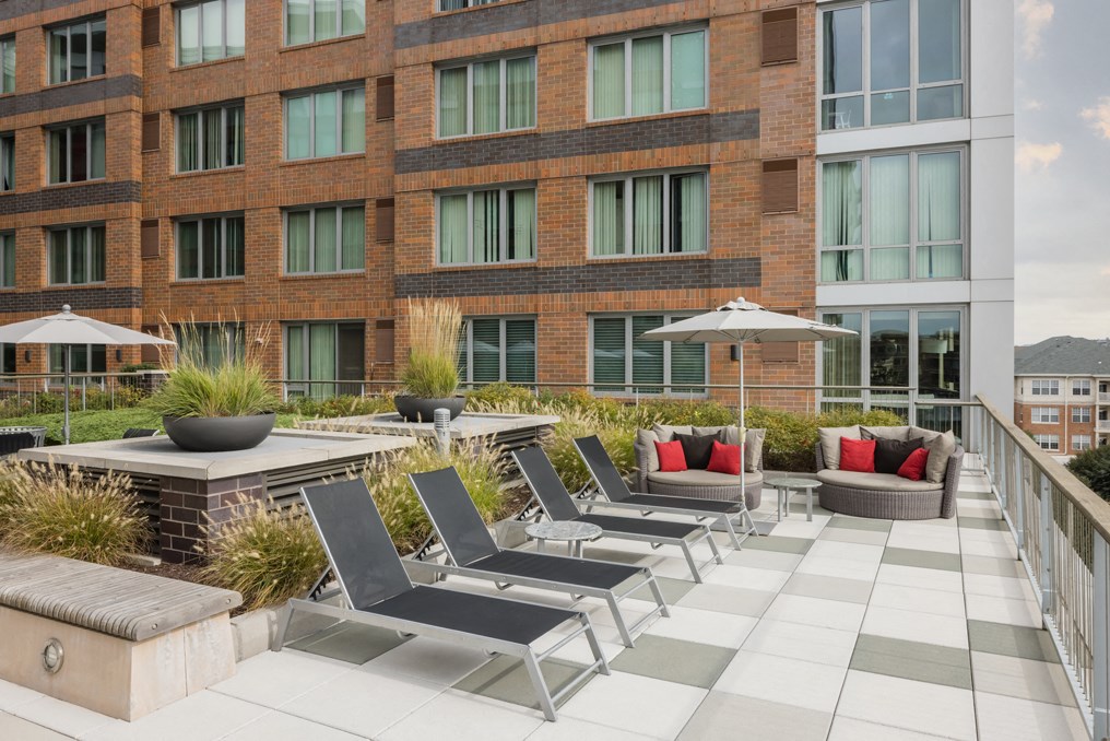 an outdoor patio with lounge chairs and a fire pit in front of a building