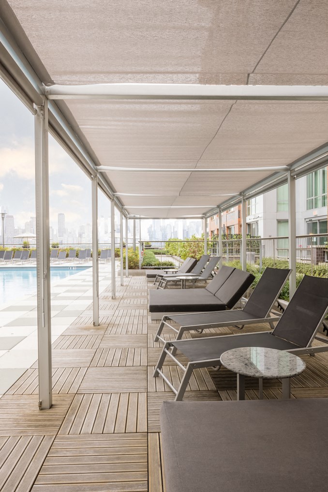 a row of lounge chairs on a deck next to a swimming pool