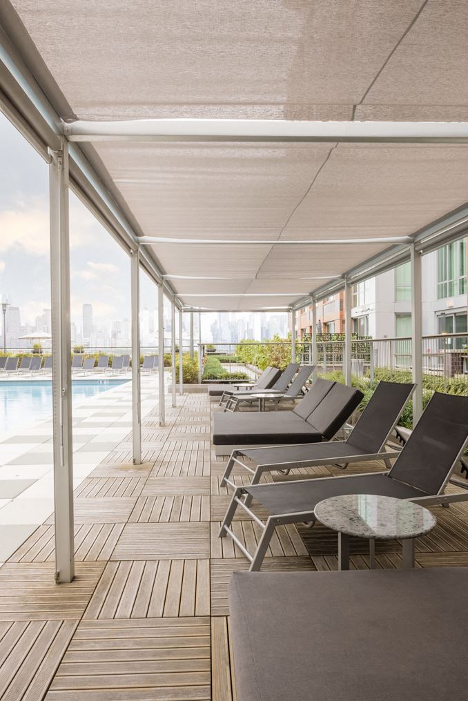 a row of lounge chairs on a deck next to a swimming pool