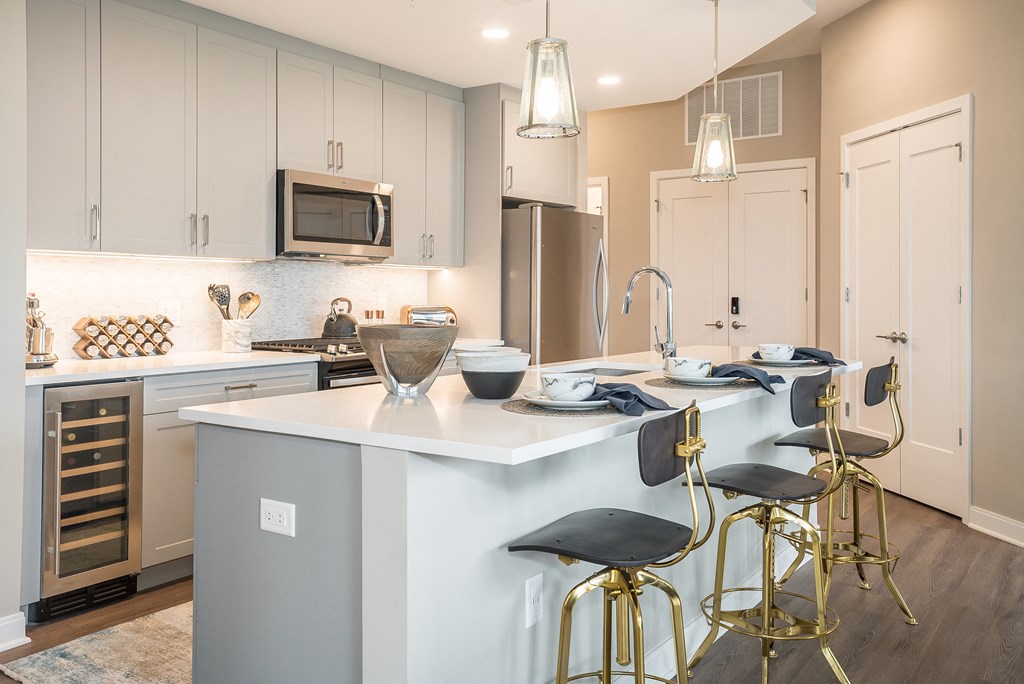 a kitchen with a white counter top and gold bar stools