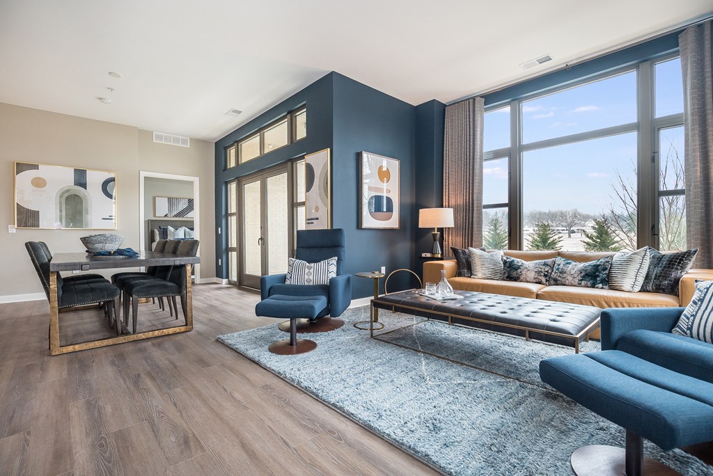 a living room with a blue accent wall and large windows