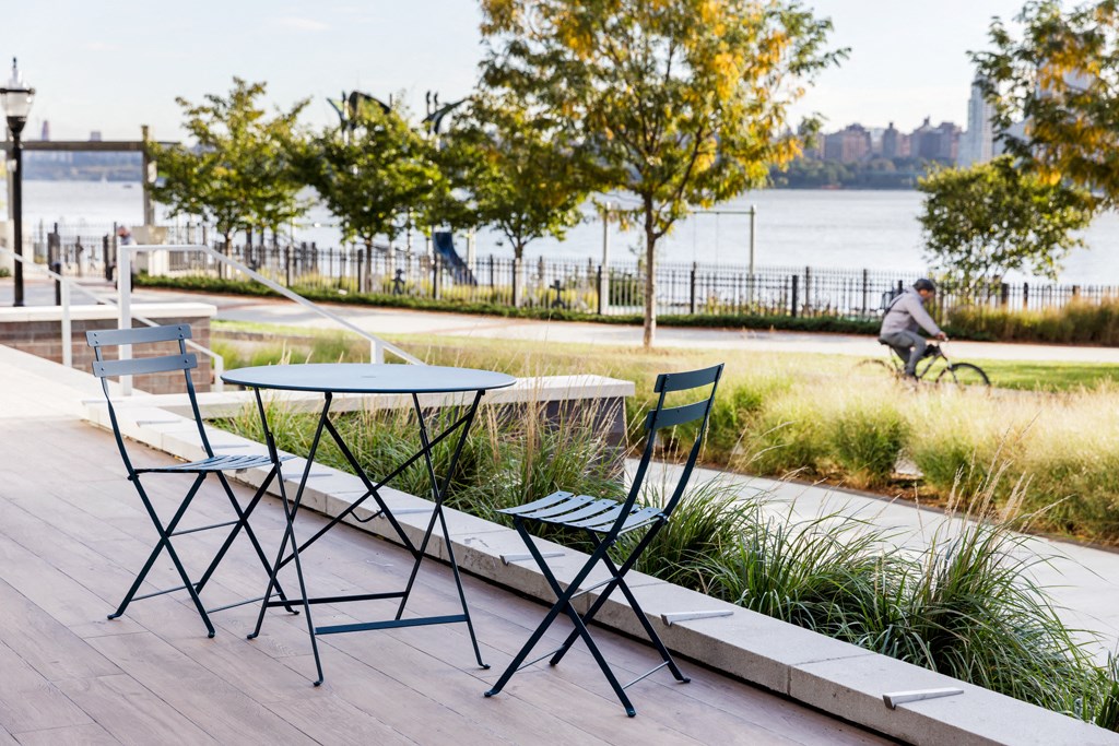a group of tables and chairs on a deck overlooking the water