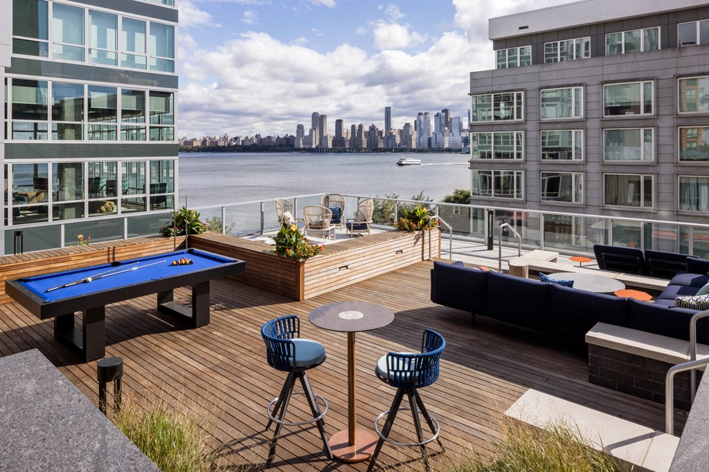 a roof deck with a pool table and a view of the city