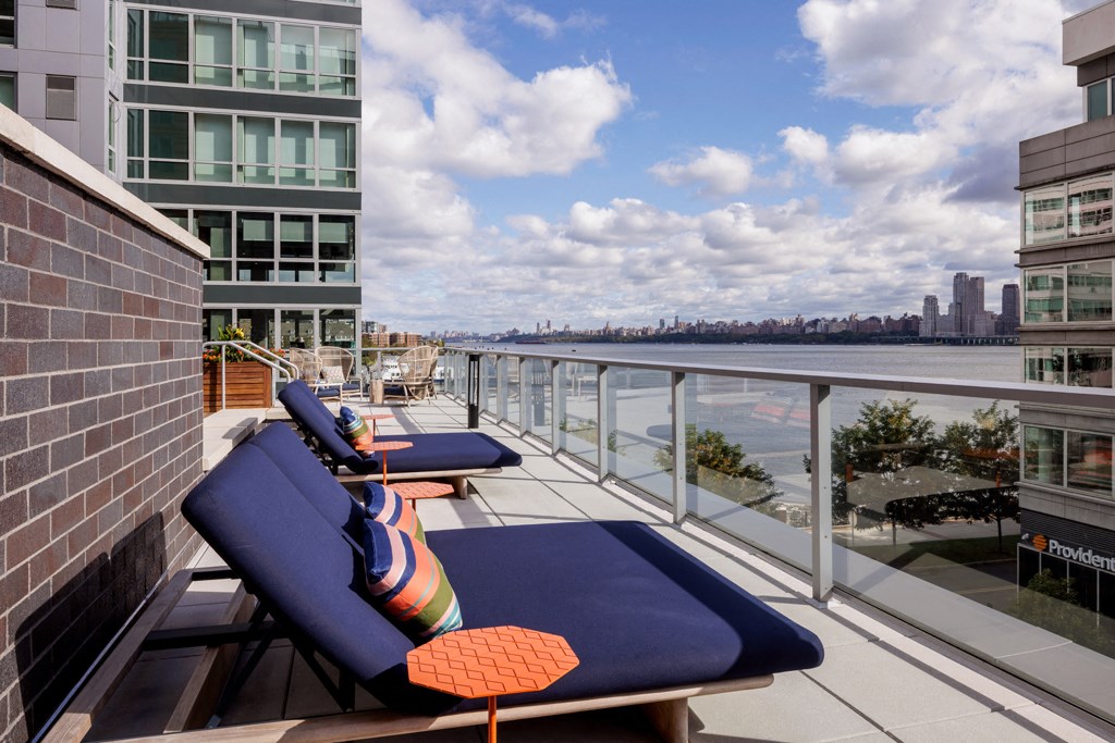 a view of the water from a balcony with blue lounge chairs