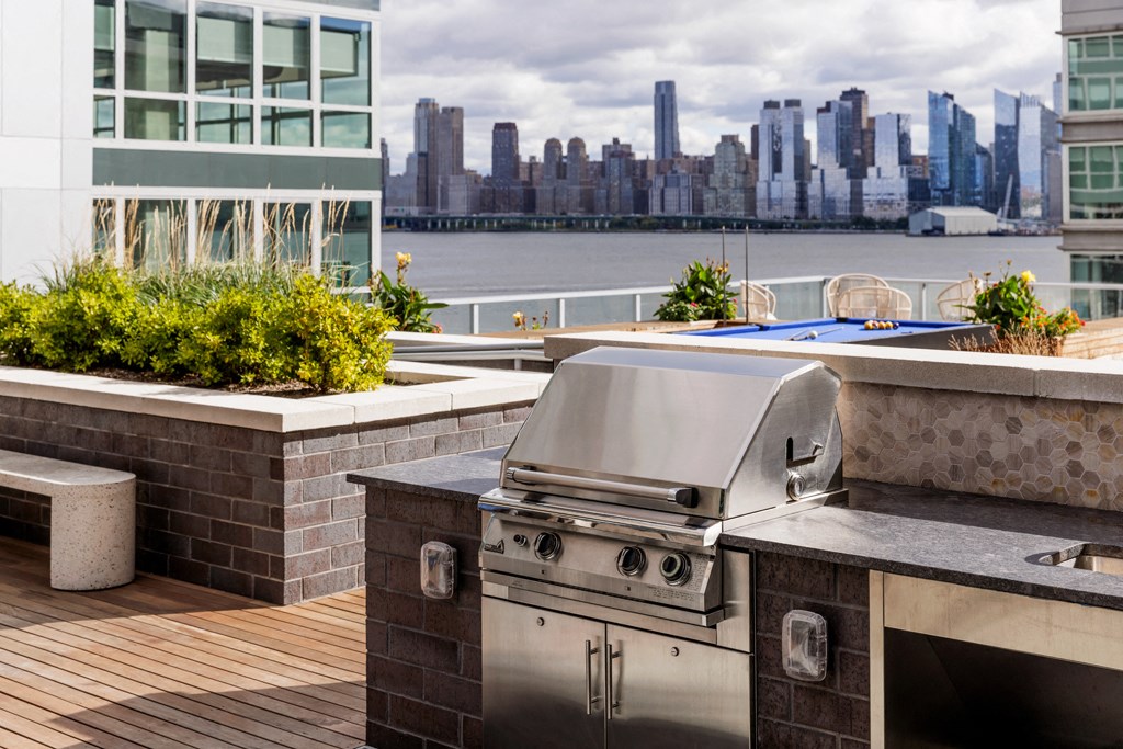 a stainless steel grill on a deck with a city skyline in the background