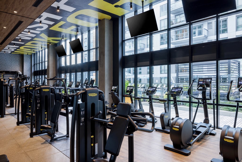 a gym with cardio equipment and windows in a building
