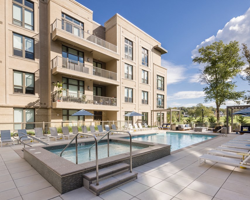 a swimming pool with lounge chairs in front of a building