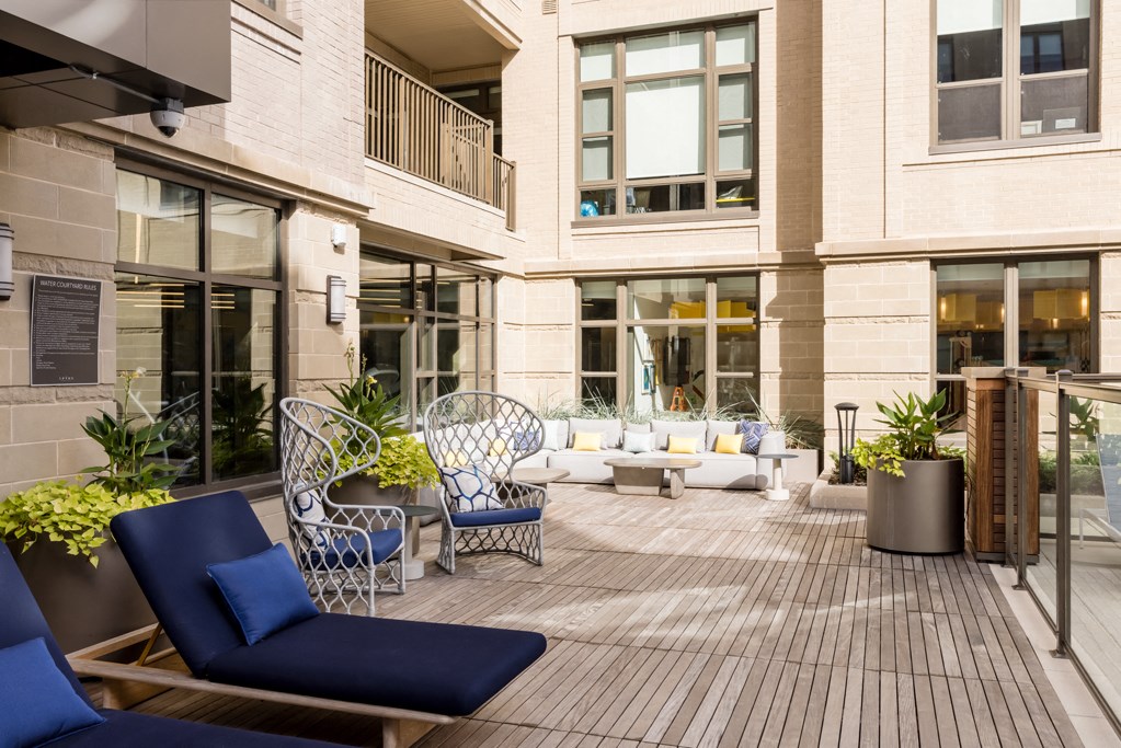 a patio with chairs and tables in front of a building