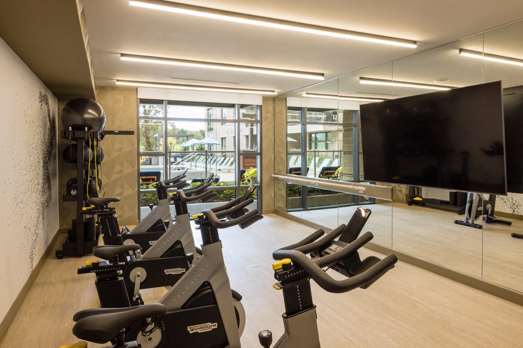 a workout room with cardio machines and a large screen tv
