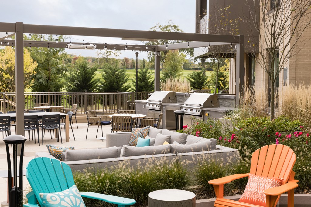 a patio with chairs and tables and a grill