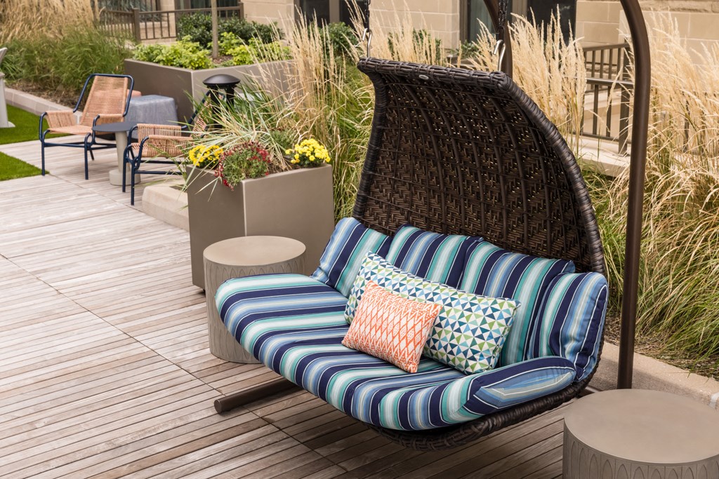 a swing chair on a deck with pillows on it