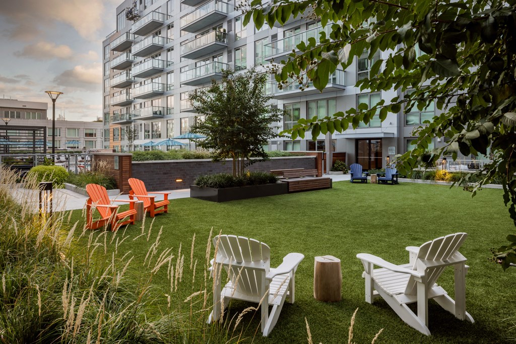 a communal lawn with chairs and a tree in an apartment building