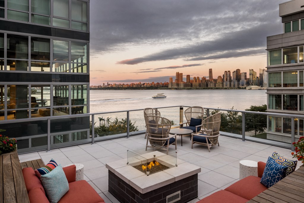 the terrace has a fireplace and a view of the water and the city skyline