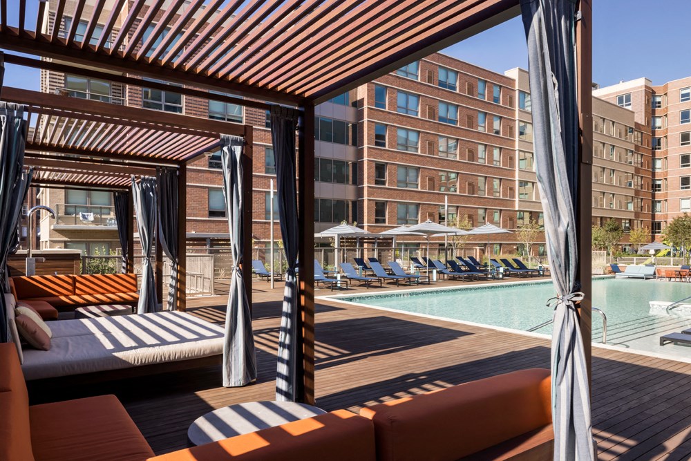 a hotel pool with lounge chairs and umbrellas in front of a building