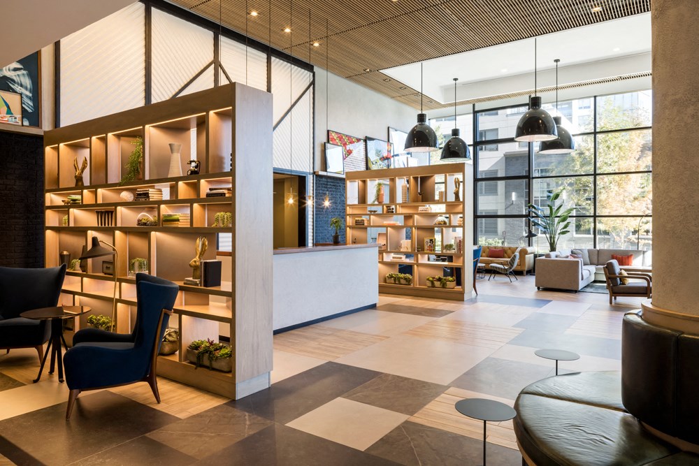the lobby of a hotel with a reception area and tables and chairs