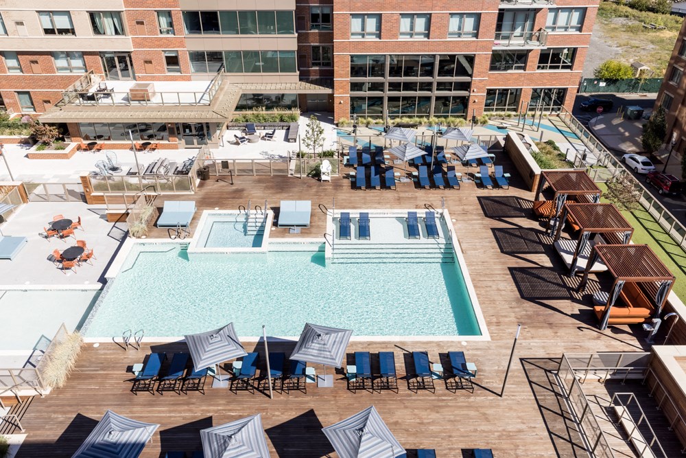 an aerial view of a pool with chairs and umbrellas