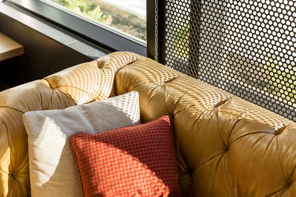 a leather couch with pillows on it next to a window