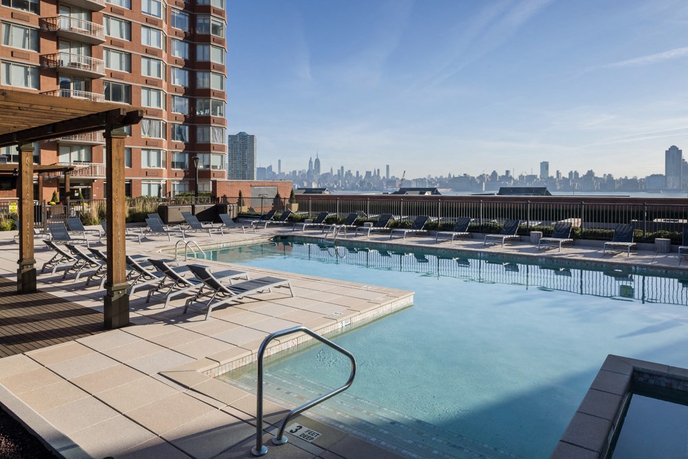 an outdoor pool with a city skyline in the background