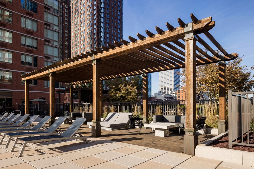 a row of chaise lounge chairs under a wooden canopy on a patio