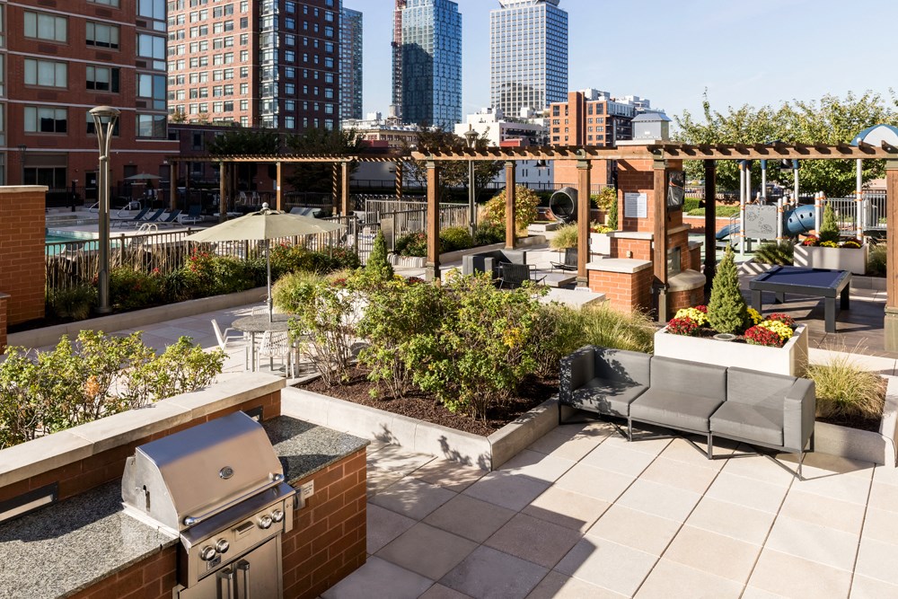 a rooftop patio with a grill and a city skyline in the background