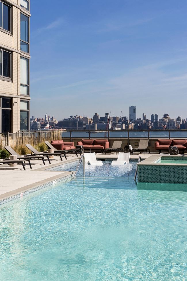 a swimming pool on the roof of a building with a city in the background
