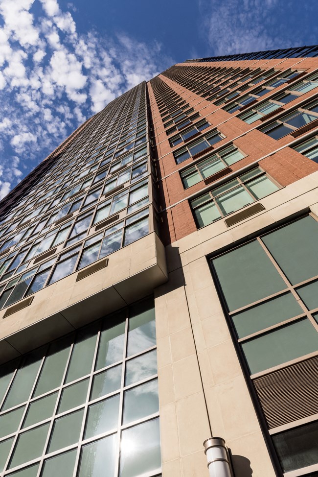 looking up at the side of a tall building with reflections of the sky