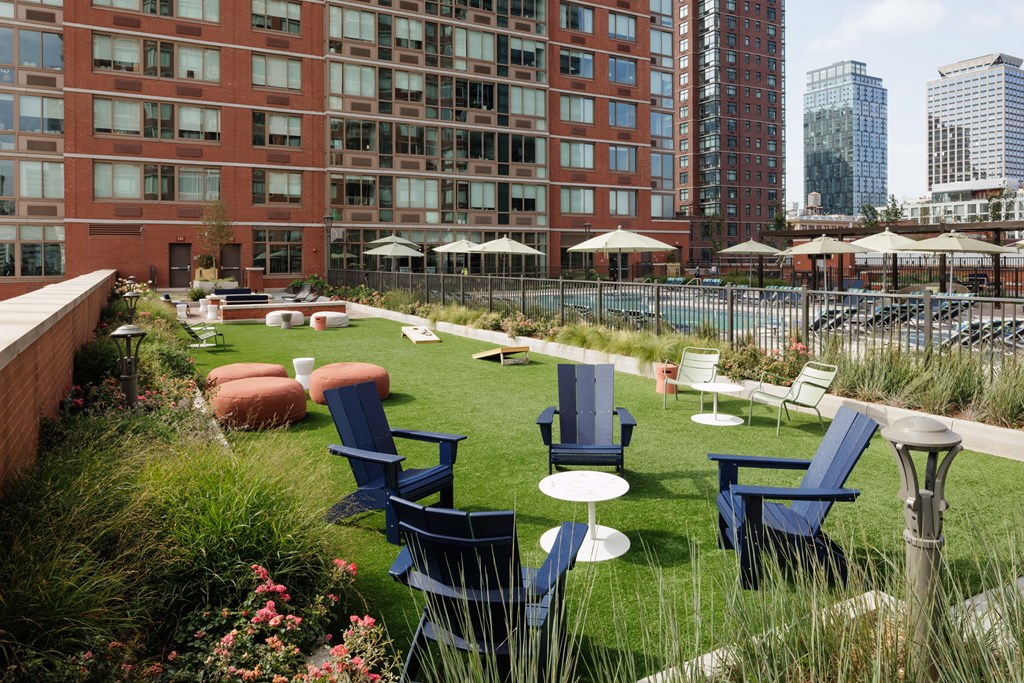 A patio with blue chairs and tables is surrounded by a grassy area.
