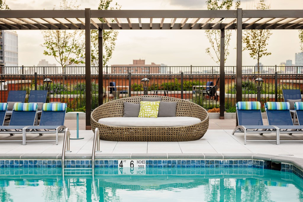 A pool with a wicker sofa and chairs around it.