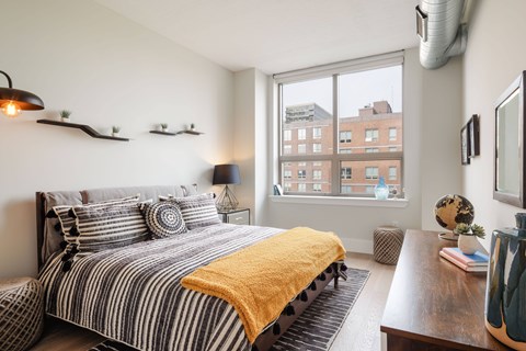 A bedroom with a bed and a window overlooking a city.