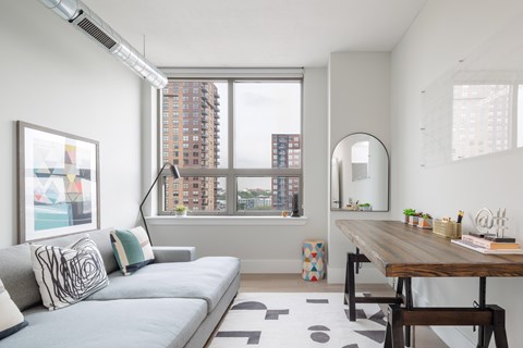 A modern living room with a grey sofa and a wooden table.