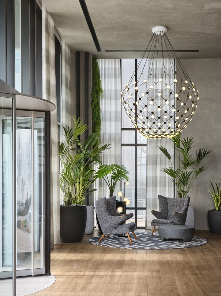 a lobby with chairs and plants and a chandelier