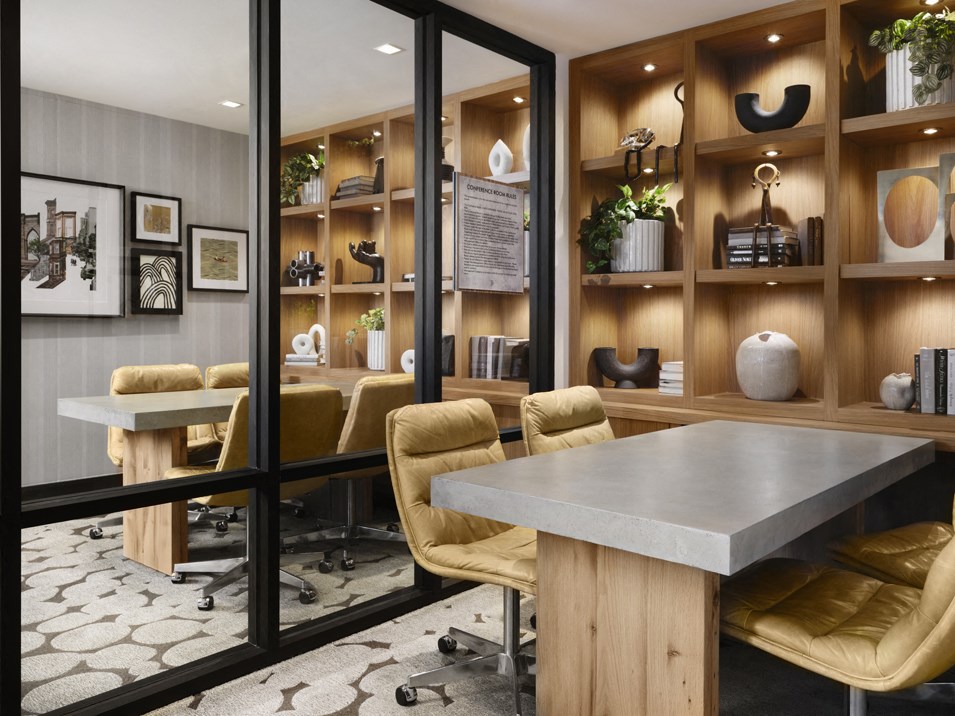 a conference room with tables and chairs and a wall of shelves