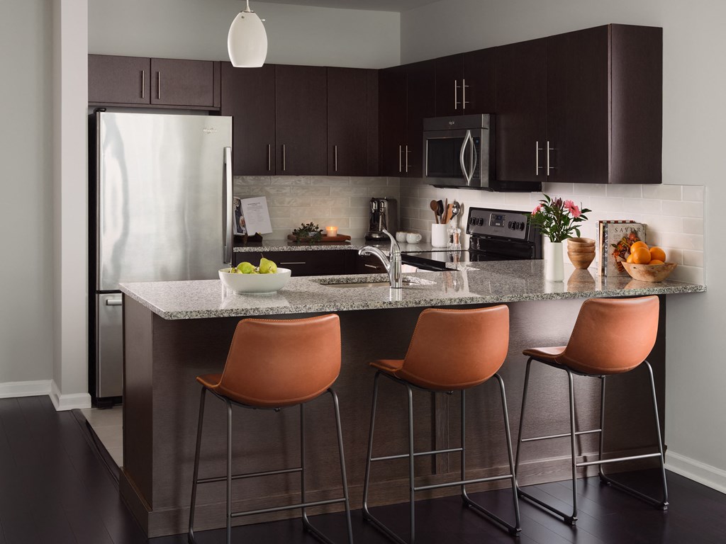 a kitchen with a marble counter top and a stainless steel refrigerator