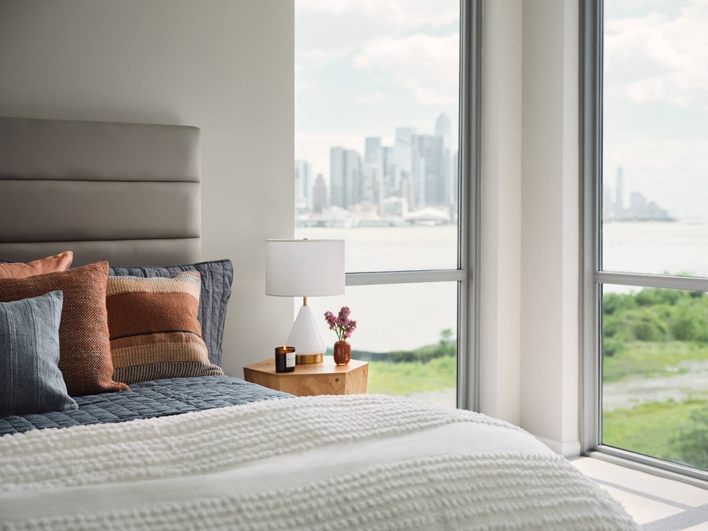 a bedroom with a bed and a window with a city view