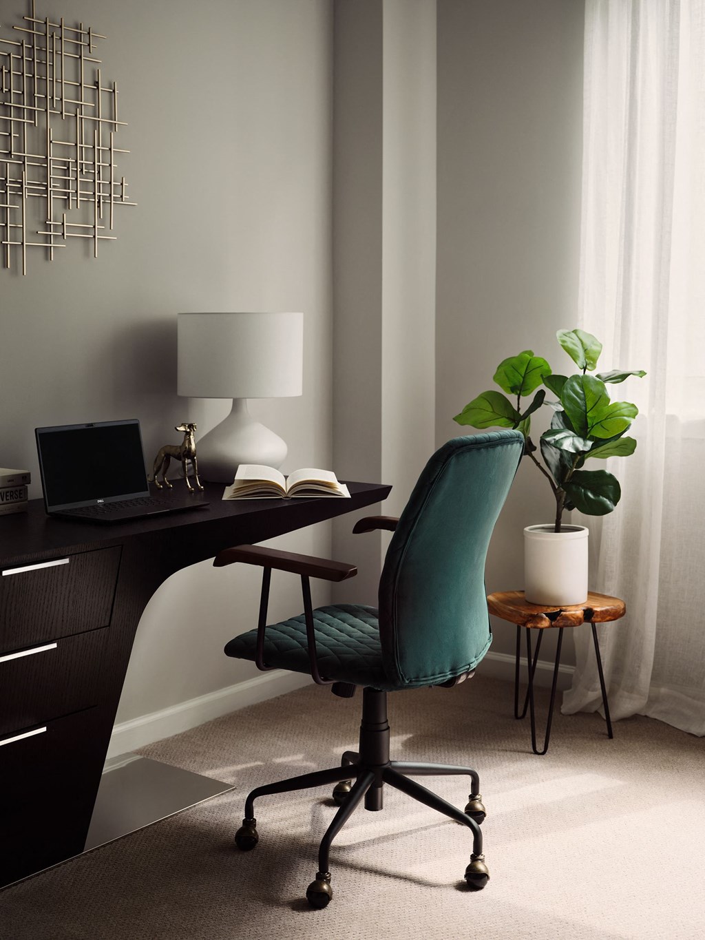 a desk with a chair and a table with a lamp and a plant